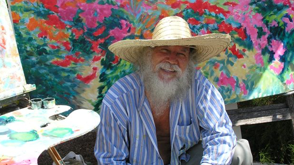Picture of St Maarten artist Roland Richardson with Flamboyant Tree paintings