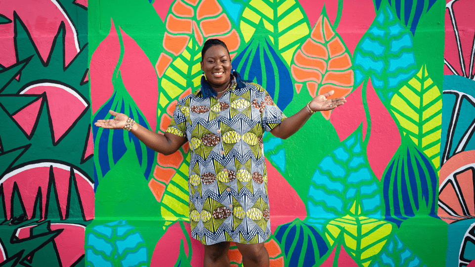 Zillah Duzon Hazel standing in front of her own Mural Artwork in Philipsburg