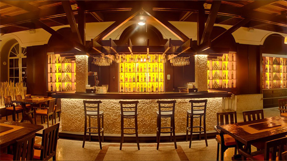 Bar with liquor display and dining tables at Melange International Grill