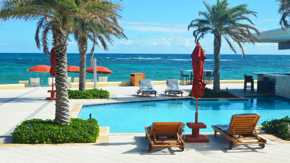 Aquamarine blue sea with palm tree and pool bar in foreground at Dawn Beach Club st Marteen