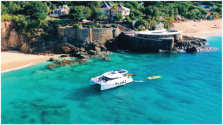 Historical wall, catamaran and bluest water in the Caribbean on the Baie Rouge Beach, St Maarten / St Martin