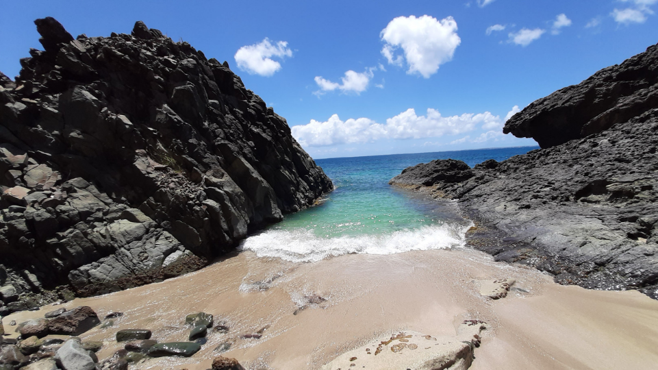 Rocks, sand and blue water on the Lovers Beach, hike away from the road of St Martin
