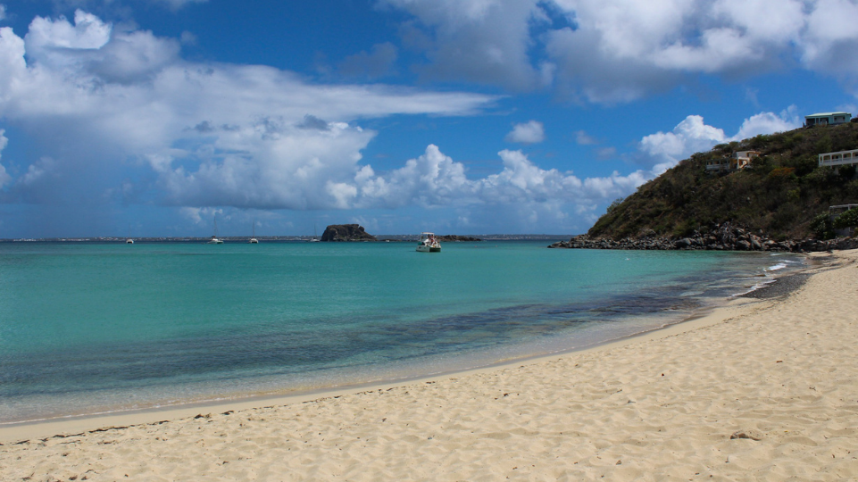 Petite Plage of St Martin with blue water and St Martin's hills far back on the picture