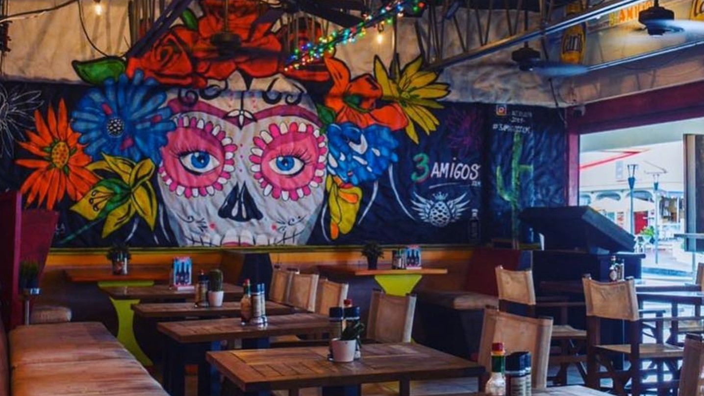3 Amigos restaurant with tables and mural of a skull