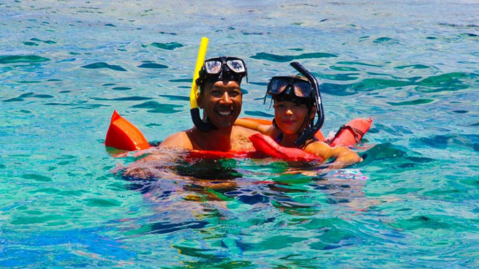 Father and girl in blue sea with snorkels on SXM