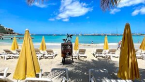 A view of KIm Sha Beach in Simpson Bay with yellow beach umbrellas and brown beach beds