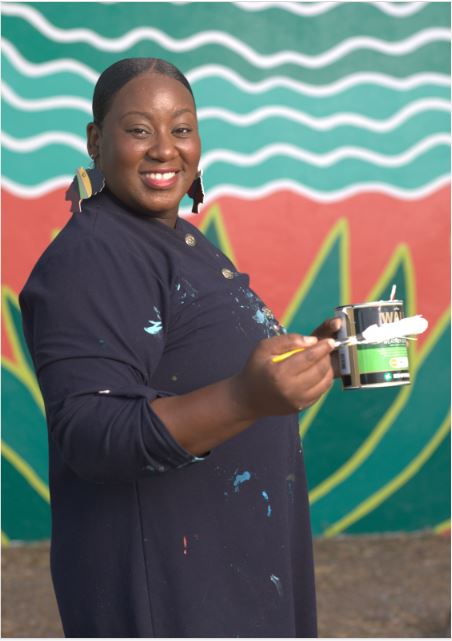 Zillah Duzon Hazel standing in front of her own painted mural in Philipsburg St Maarten, Art St Maarten, Mural Walk Philipsburg