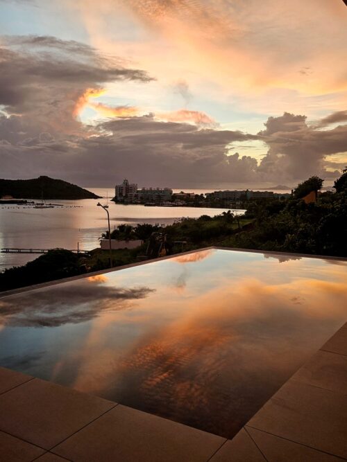 A pool reflects the clouds passing by the Oyster Bay Area in the colorful Caribbean sunrise.