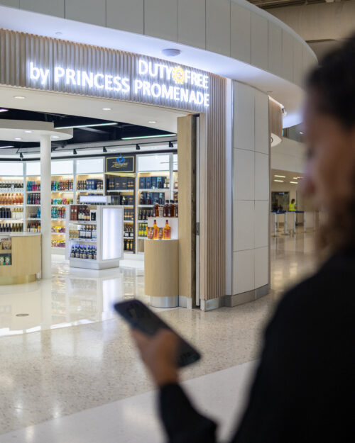 person standing in front of a duty free shop at princess juliana international airport