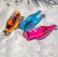 3 toppers rhum bottles laying in de sand on a beach in sint maarten