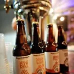 4 local crafted beer bottles standing in front of a beer tap at Pelikaan's brewery