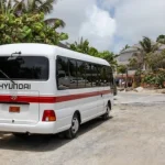 White bus with red stripe parked next to the road in st maarten