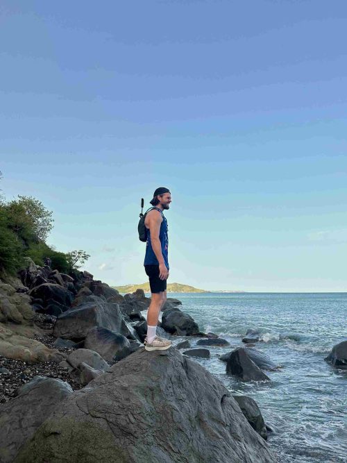 Remi Prinsen on the rocks next to the sea doing the Wilderness Hike