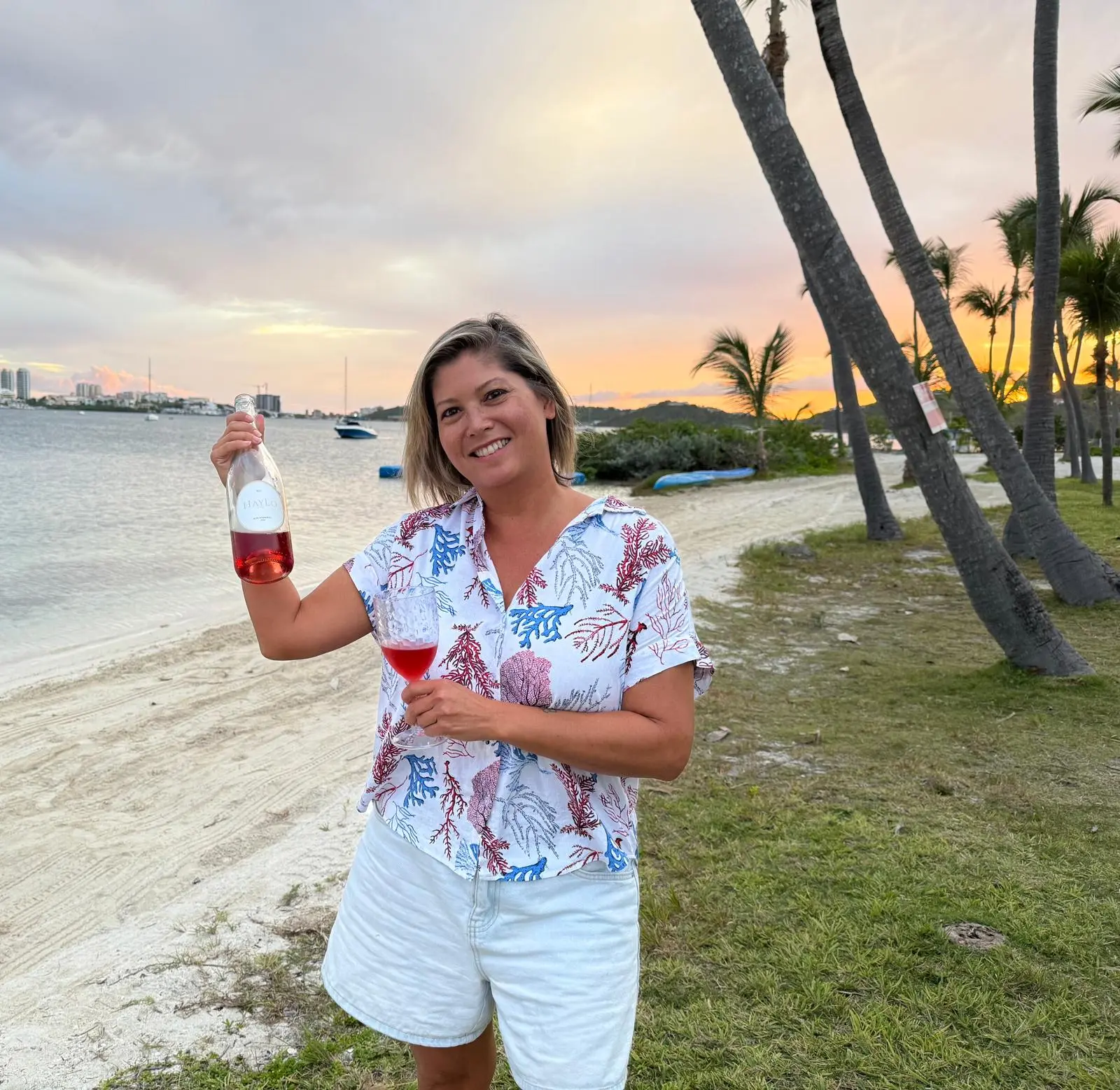 Candice Cancino on the beach with a bottle of wine
