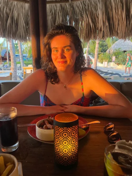 Woman sitting at a restaurant with sunset rays shining on her face