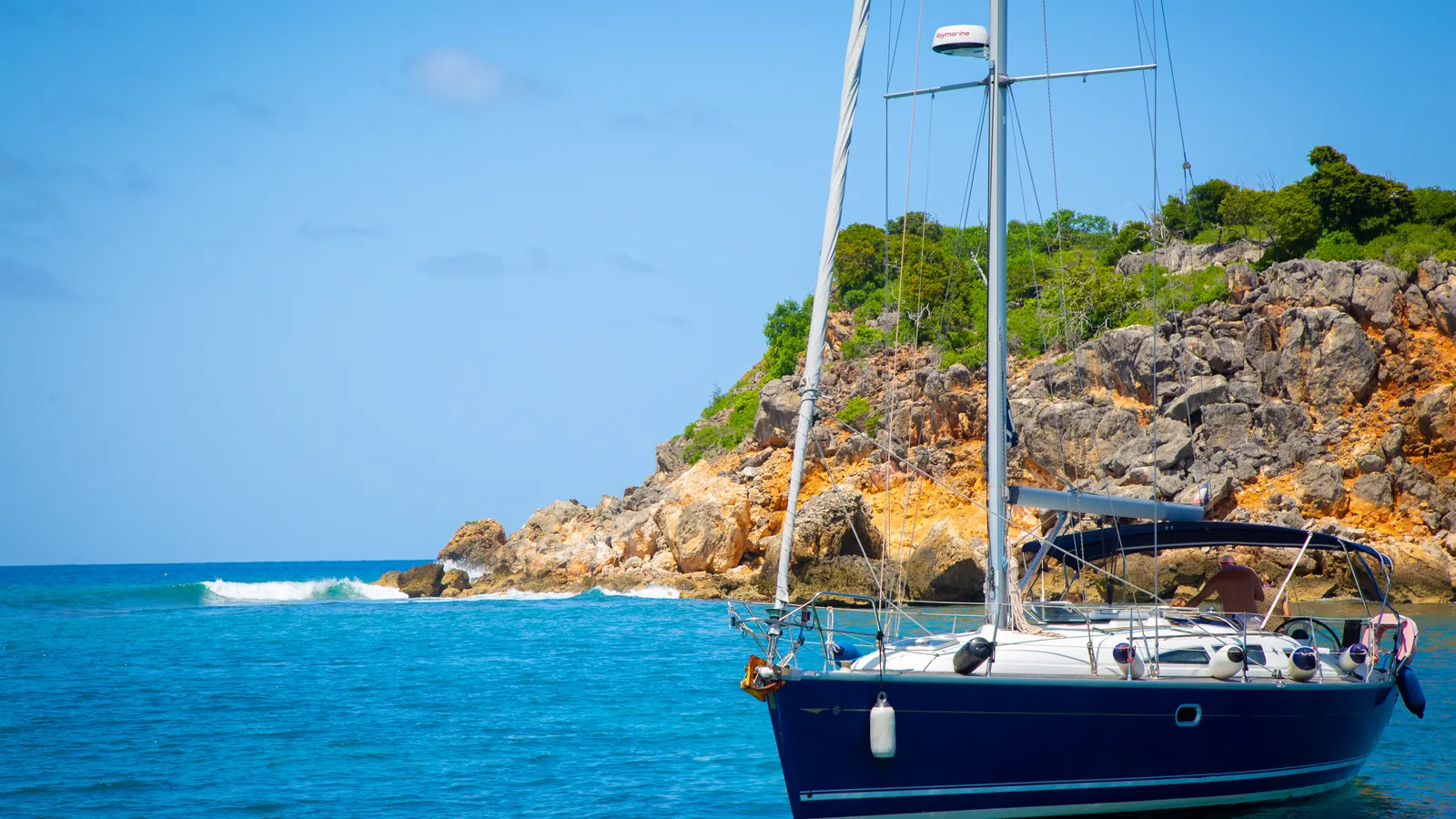 Sailboat anchored beside the rocky coast of Tintamarre Island.