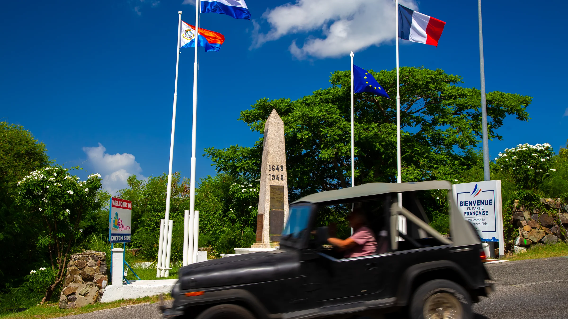 Jeep passes the French-Dutch border monument in St. Maarten.