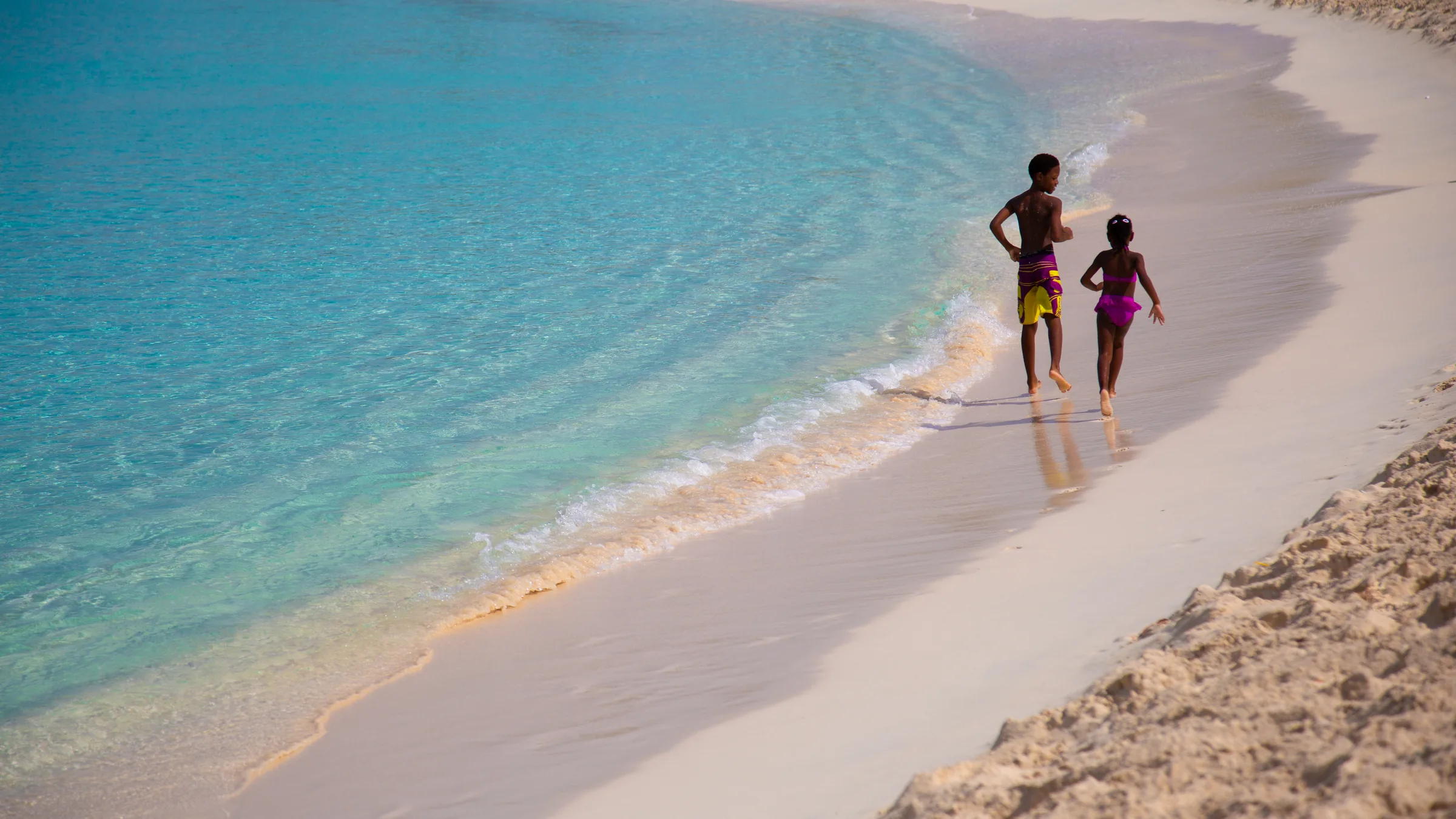 Two children run along the shoreline at Mullet Bay in St. Maarten.