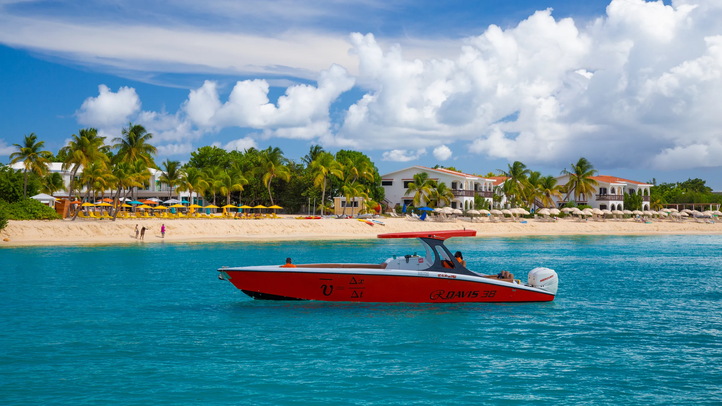 Motorboat crosses turquoise water near a Caribbean island beach.
