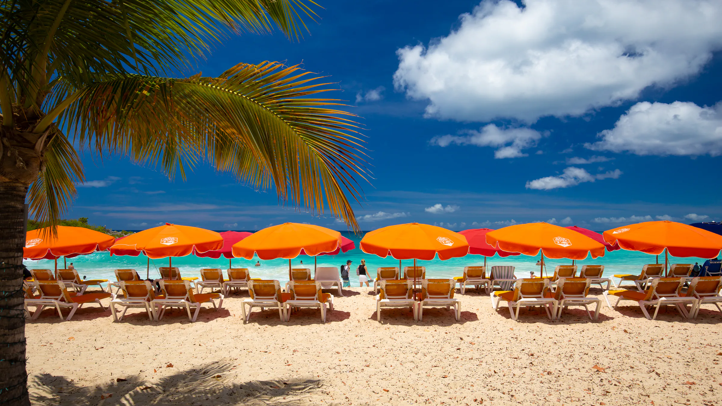 Orange umbrellas and beach chairs line the sand at Mullet Bay in St. Maarten.