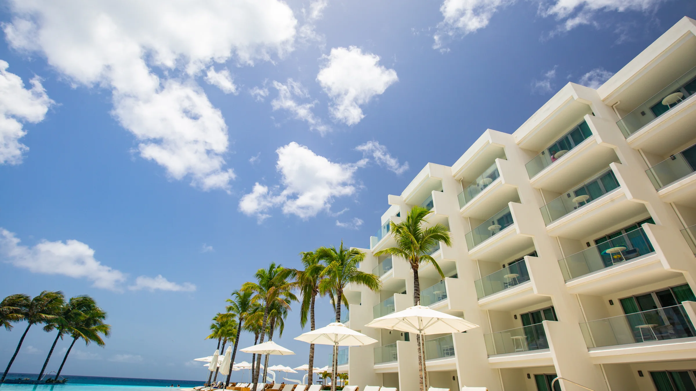 White resort building, palm trees, and turquoise water in St. Maarten.