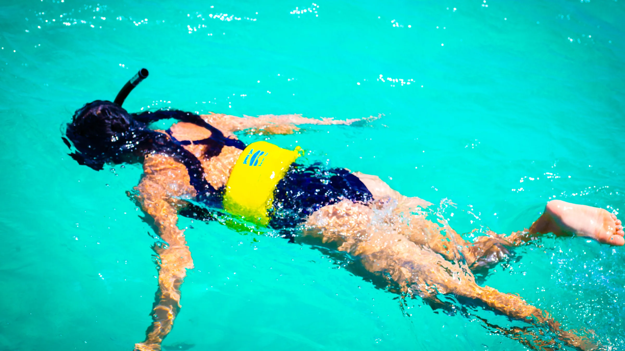 Snorkeler swims through clear turquoise water off St. Maarten.