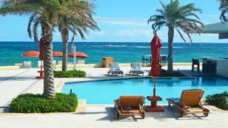 Aquamarine blue sea with palm tree and pool bar in foreground at Dawn Beach Club st Marteen